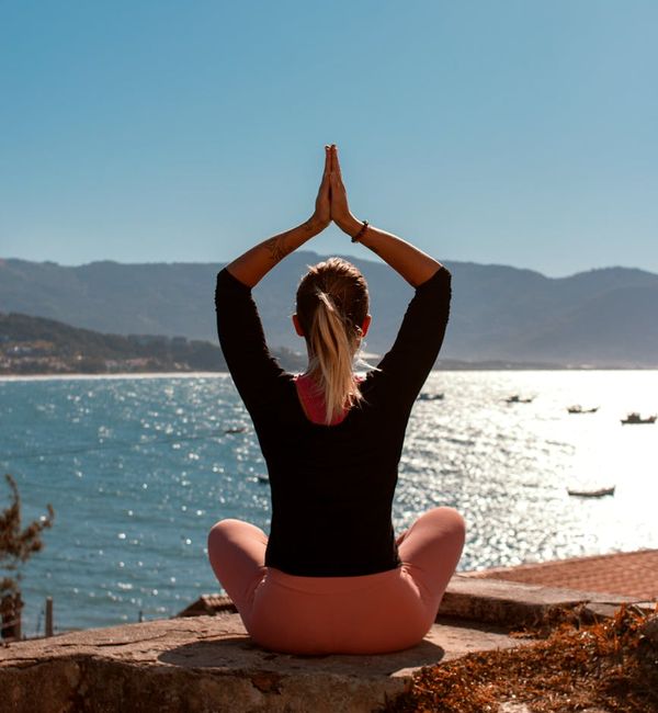 Runner sitting in a calm yoga pose on a cliff overlooking the sunrise.